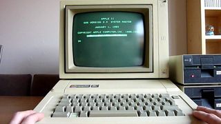 A photograph of a person staring at an Apple II green display.